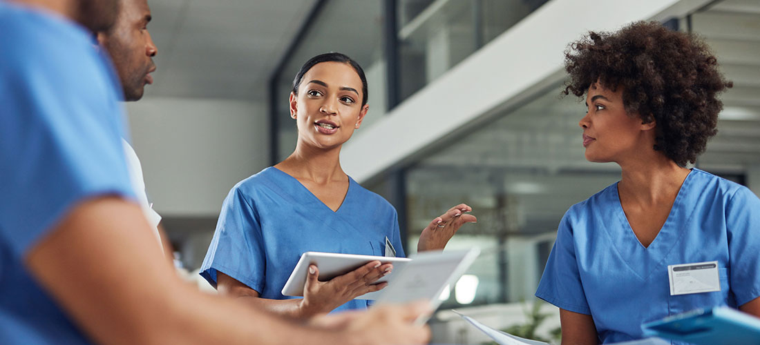 Nurse holding chart and talking to other nurses.