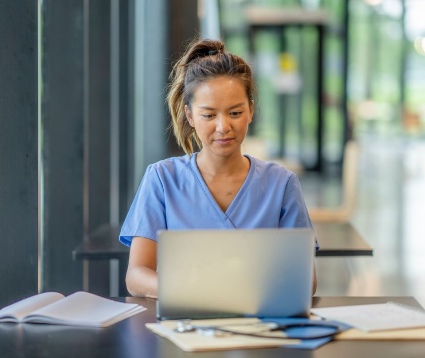 Nurse in scrubs on laptop