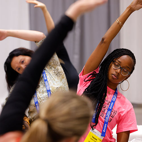 Wellness_500x500 Group of people doing stretching exercises in expo hall.