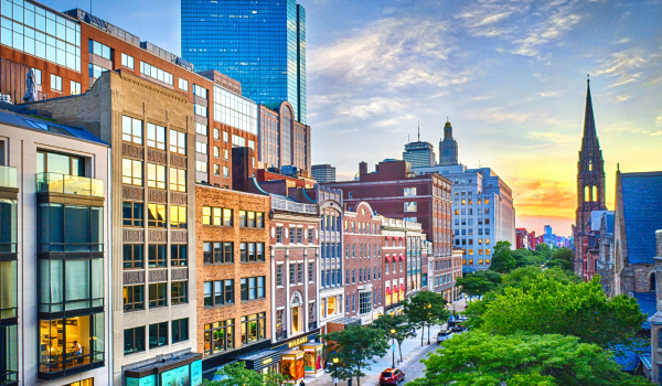 Street in Boston with skyline of buildings and trees.